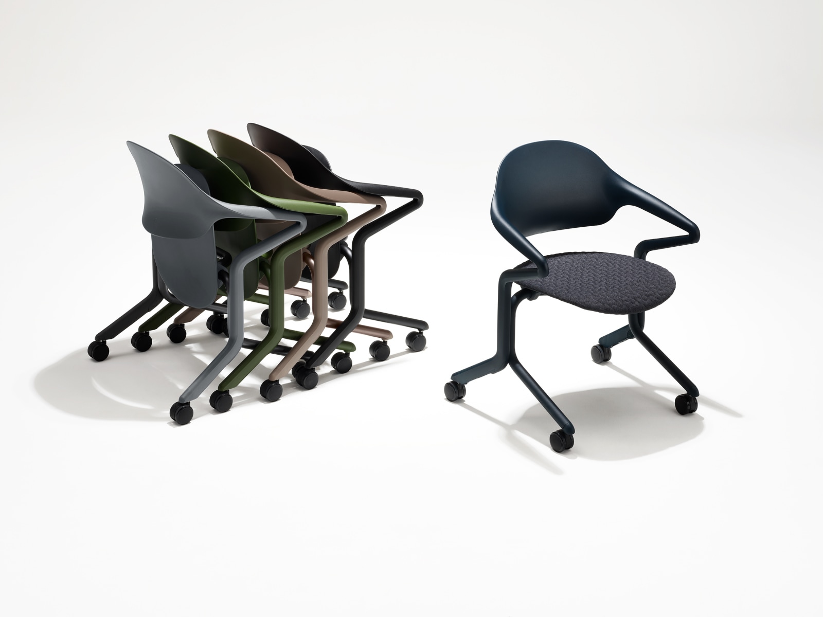 Quatro cadeiras empilháveis Fuld em diversas cores e acabamentos aninhadas em um grupo ao lado de uma única cadeira empilhável Fuld em Nightfall com o tecido em 3D Knit.